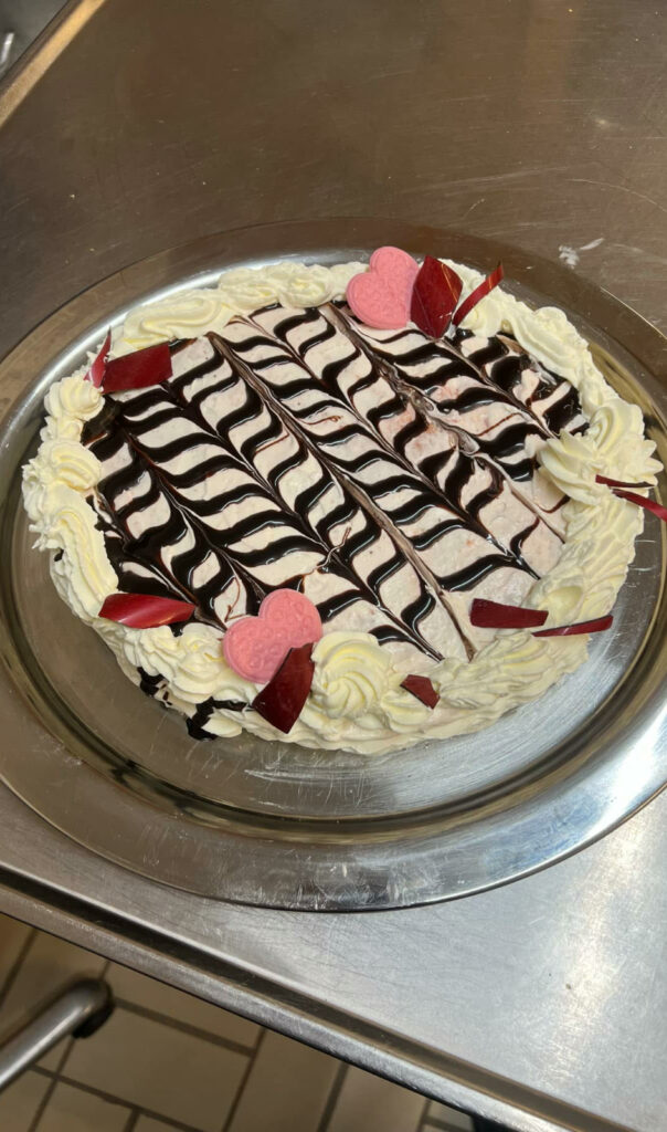 Marmoroitu syntymäpäiväkakku vaaleanpunaisilla sydämillä ja kermapursotuksilla