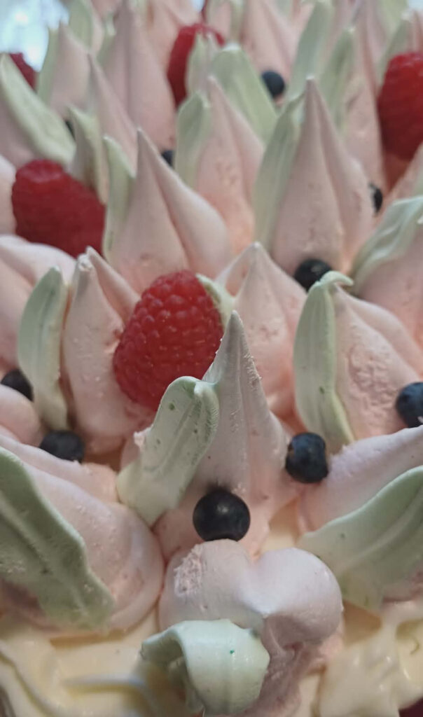 Taiteellinen lähikuva marjakakusta, jossa on pehmeän vaaleanpunaisia marenkimaisia huippuja ja tuoreita metsämarjoja